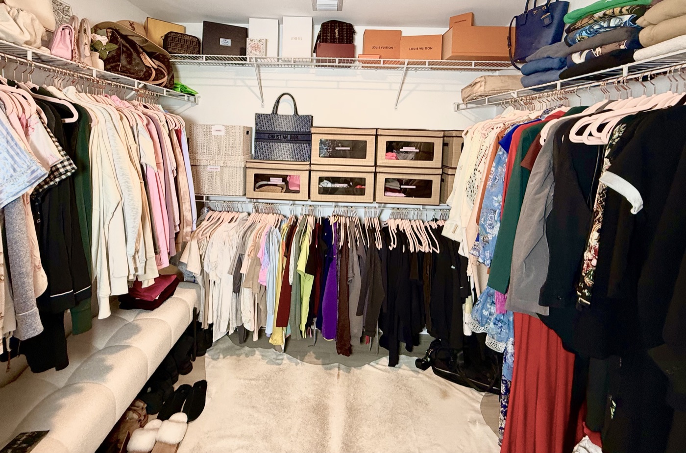 Large walk-in closet with designer boxes, labeled storage, and full clothing racks