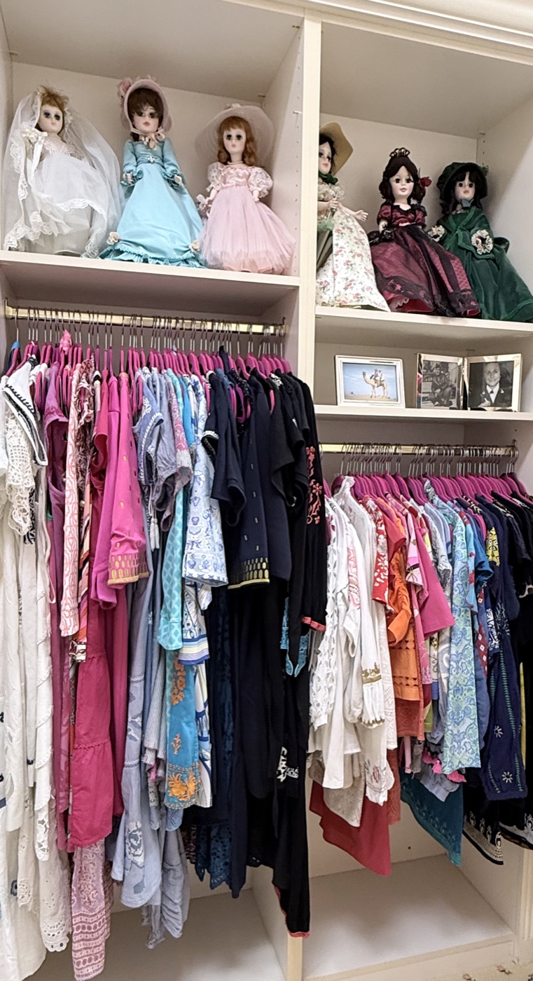 Closet with vintage doll collection and organized hanging wardrobe