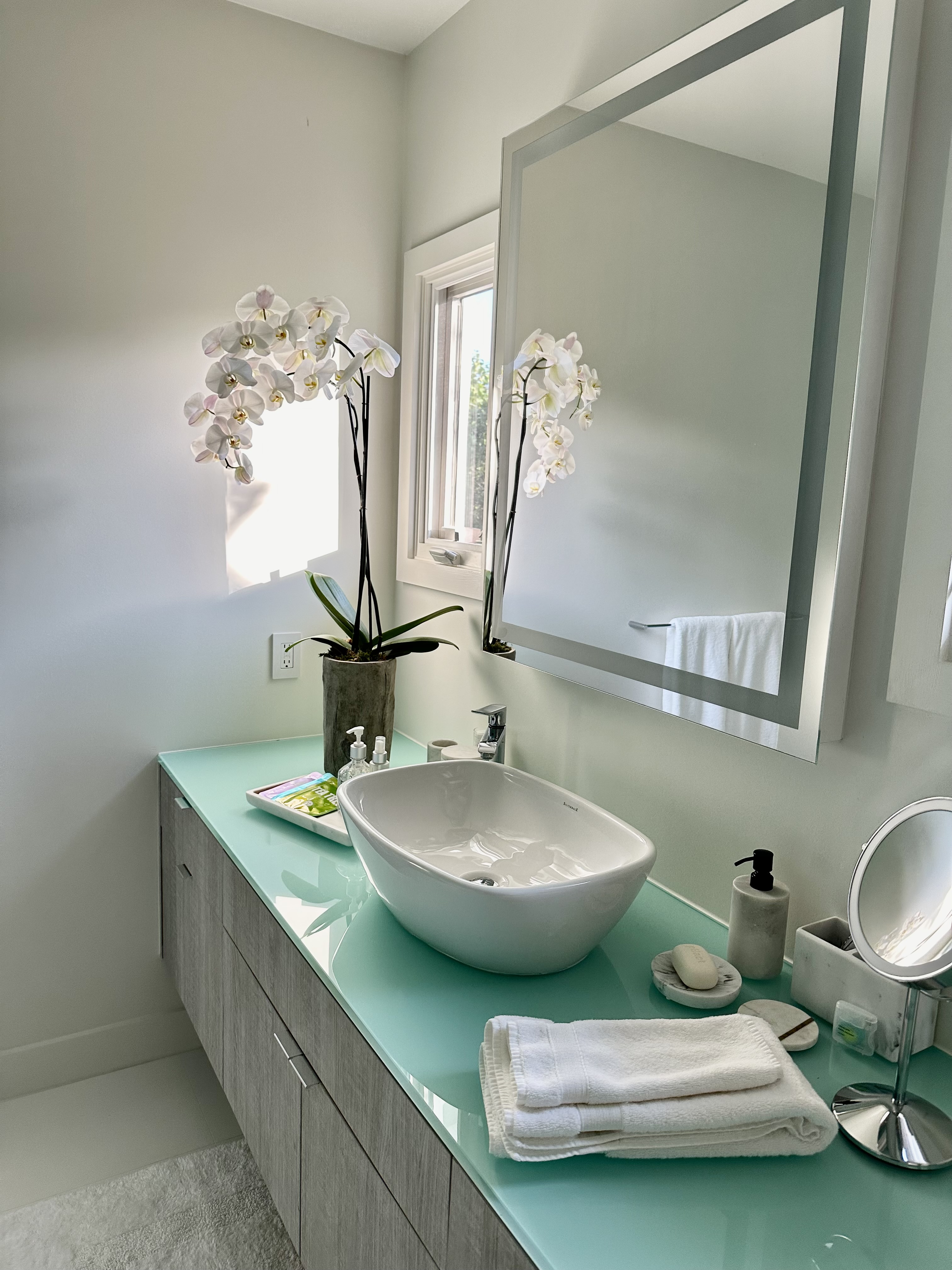 Styled bathroom vanity with vessel sink, fresh orchids, and folded towels