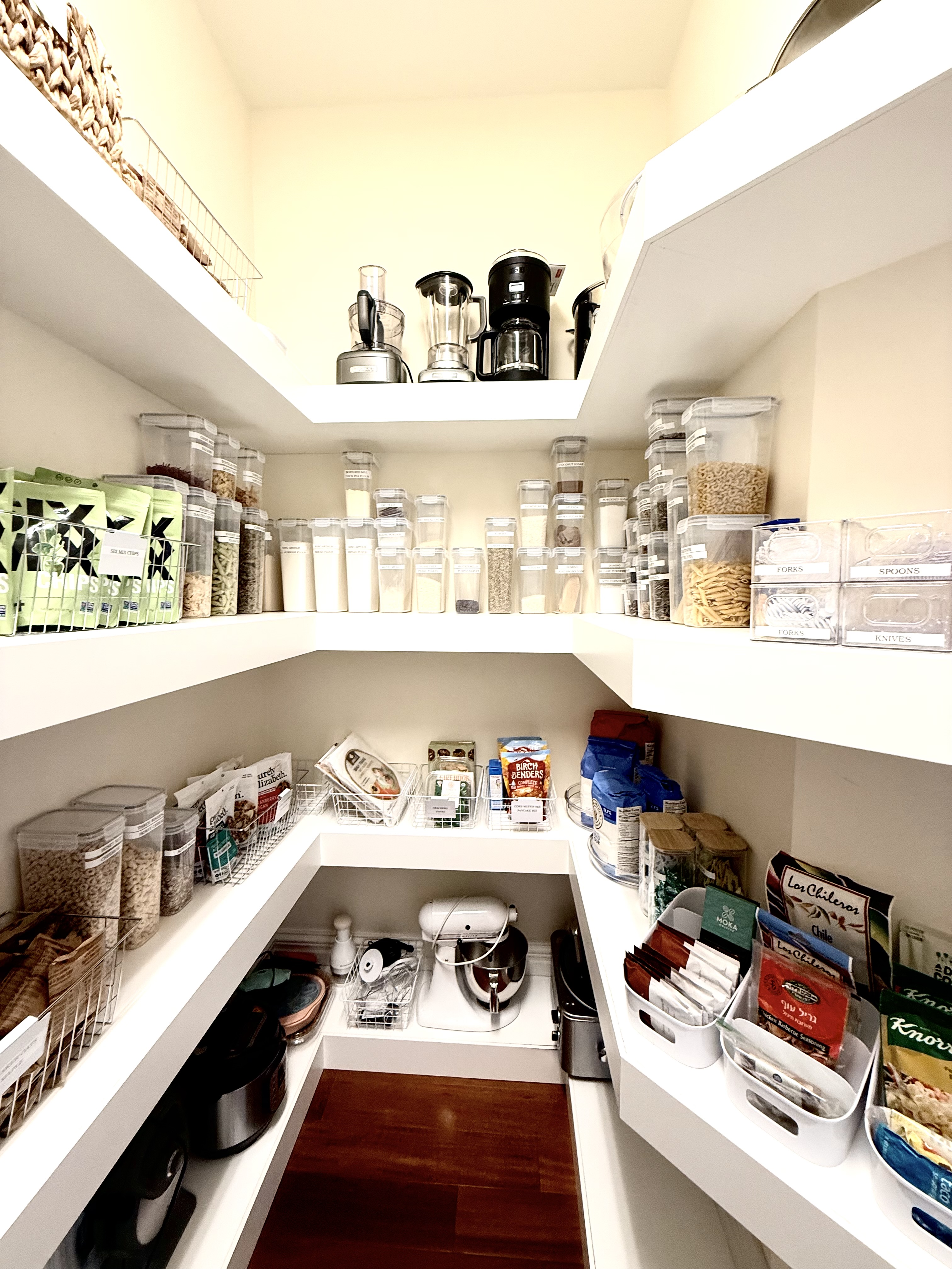 Corner pantry with labeled clear containers, small appliances, and organized shelving