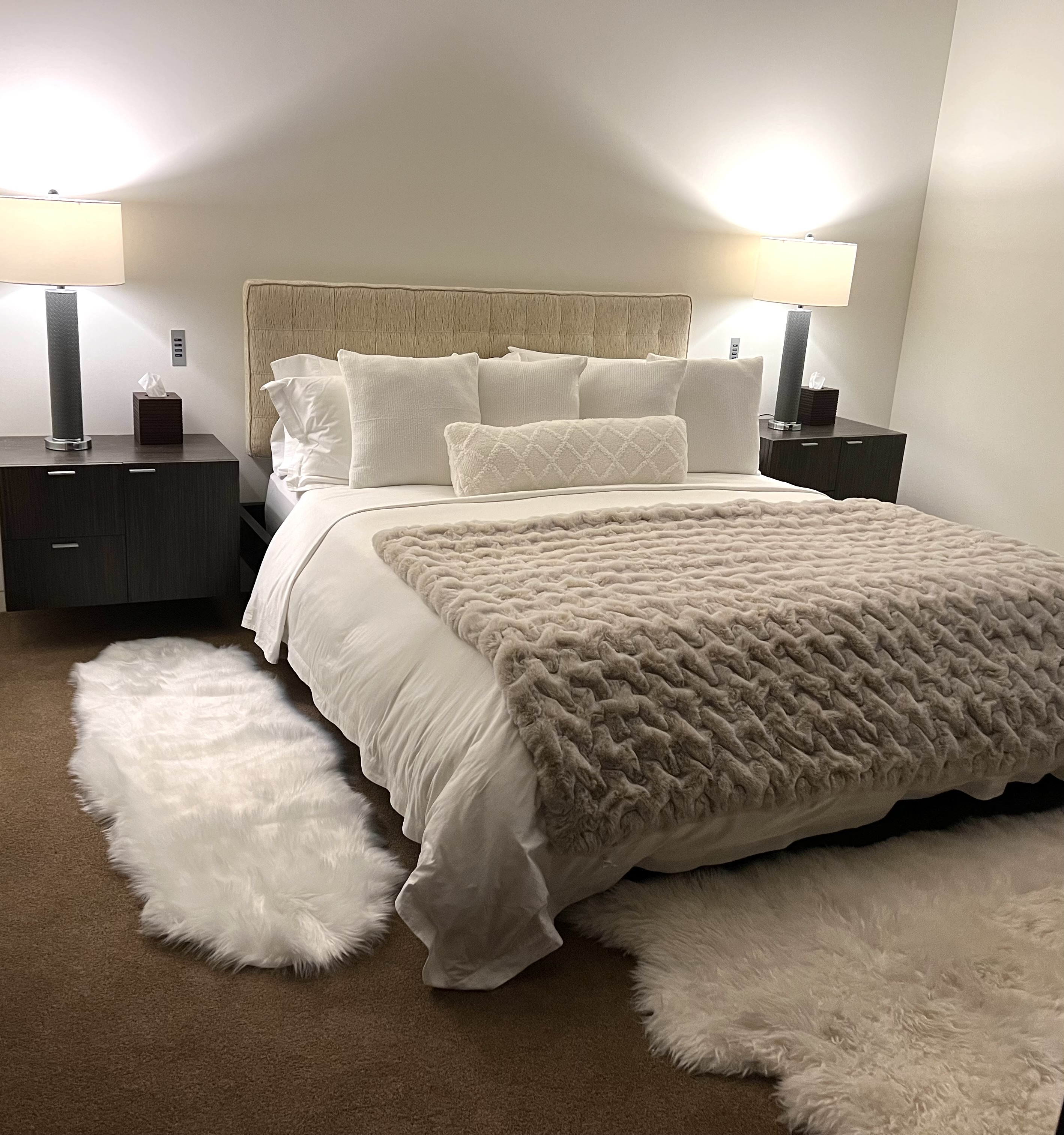 Primary bedroom styled with a plush faux-fur throw, textured pillows, and sheepskin rugs after a full room reset